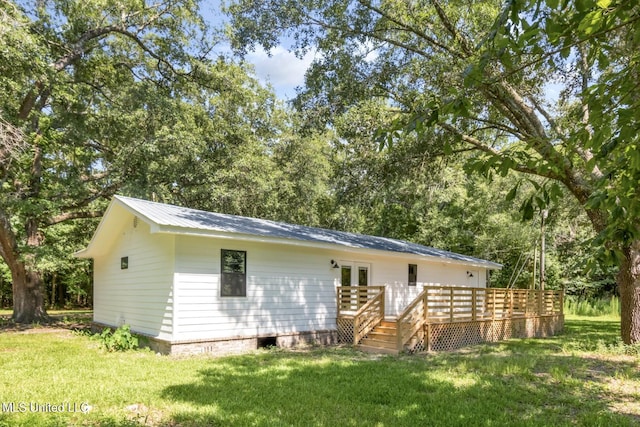 back of house featuring metal roof, a deck, a lawn, and french doors