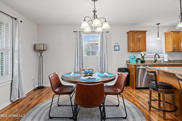 dining area with sink, an inviting chandelier, and wood-type flooring