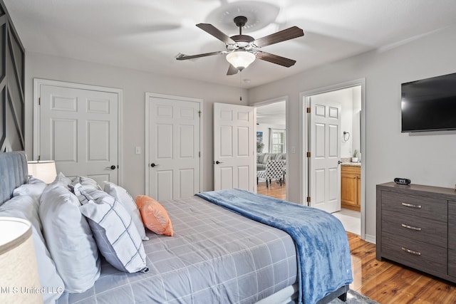 bedroom with ensuite bathroom, ceiling fan, and light hardwood / wood-style flooring