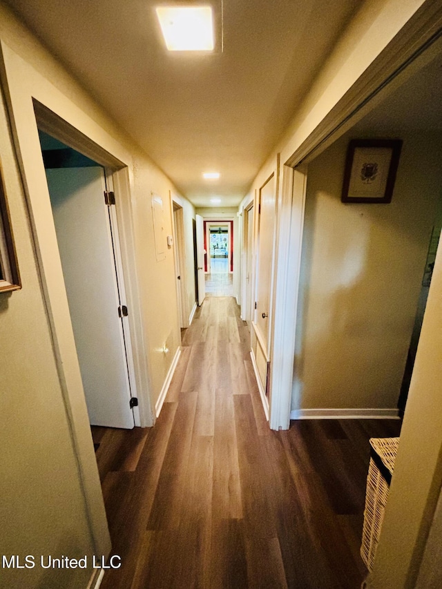 corridor featuring dark wood-style floors and baseboards