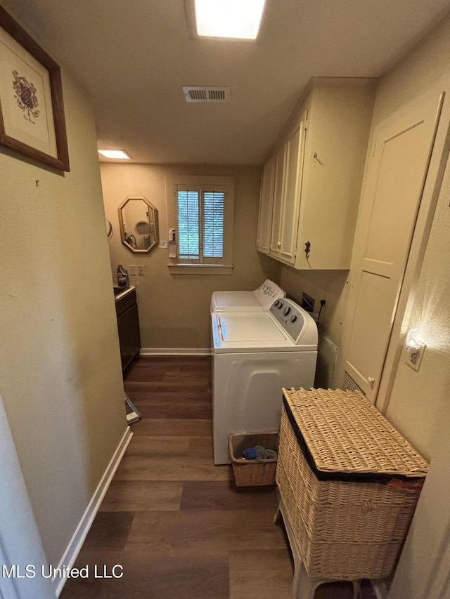 washroom with visible vents, baseboards, dark wood-style flooring, washer and dryer, and cabinet space