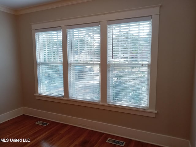 107 E Percy St, Indianola, MS 38751 - spare room featuring baseboards, dark wood-type flooring, crown molding, and healthy amount of natural light