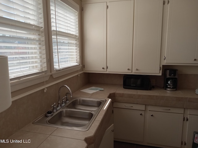 107 E Percy St, Indianola, MS 38751 - kitchen with healthy amount of natural light, white cabinets, a sink, and tile counters