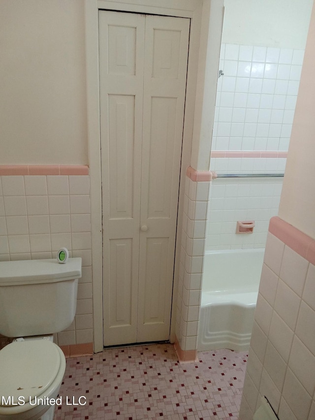 107 E Percy St, Indianola, MS 38751 - full bathroom with tile walls, a bathtub, toilet, a closet, and a wainscoted wall