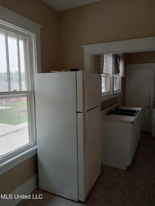 107 E Percy St, Indianola, MS 38751 - kitchen featuring freestanding refrigerator, a sink, plenty of natural light, and white cabinets