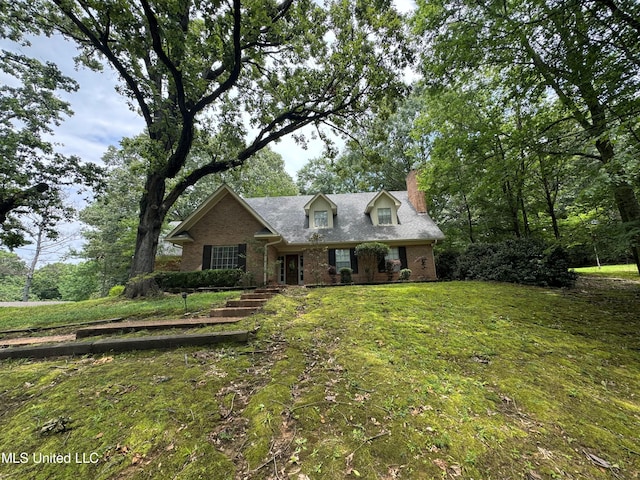 cape cod house featuring brick siding and a front lawn