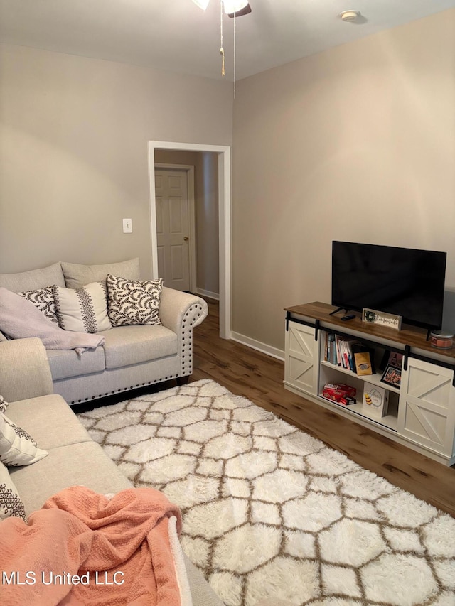 living area with baseboards, ceiling fan, and wood finished floors