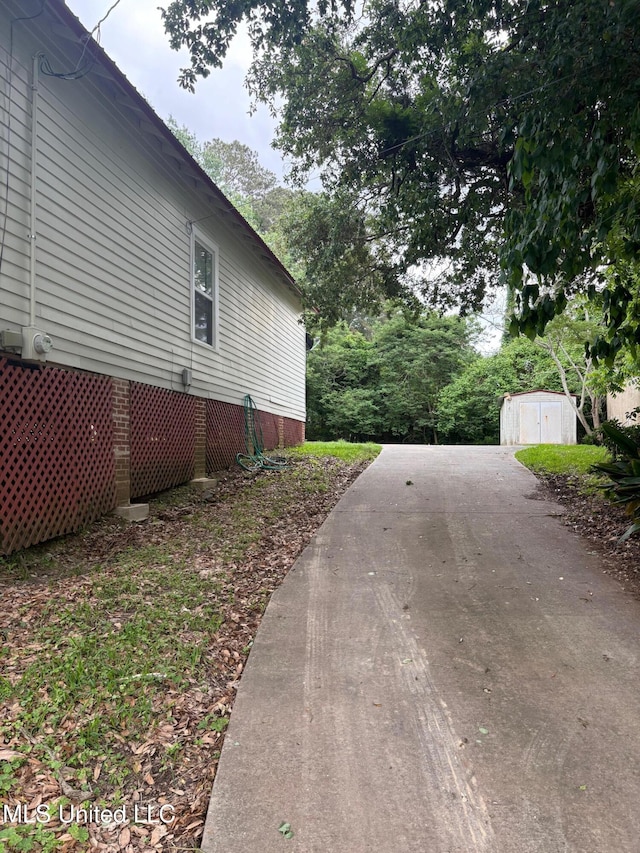 view of home's exterior with a storage shed, an outbuilding, and aphalt driveway