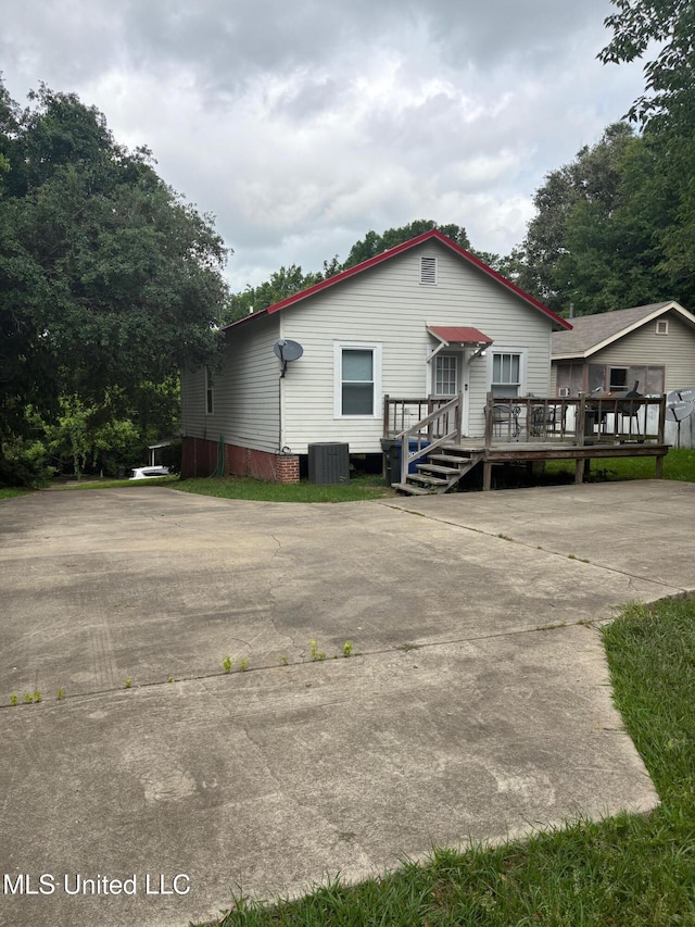manufactured / mobile home with central AC unit, a deck, and concrete driveway