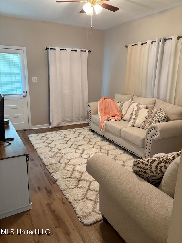 living area featuring baseboards, ceiling fan, and wood finished floors