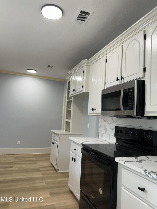 124 Holmar Dr, Brandon, MS 39047 - kitchen featuring black range with electric cooktop, stainless steel microwave, white cabinetry, decorative backsplash, and ornamental molding