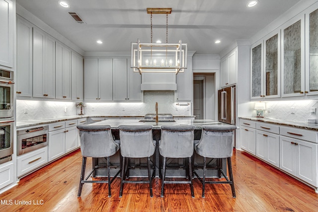 102 Silverleaf Dr, Madison, MS 39110 - kitchen featuring exhaust hood, a breakfast bar, decorative backsplash, light stone countertops, and recessed lighting