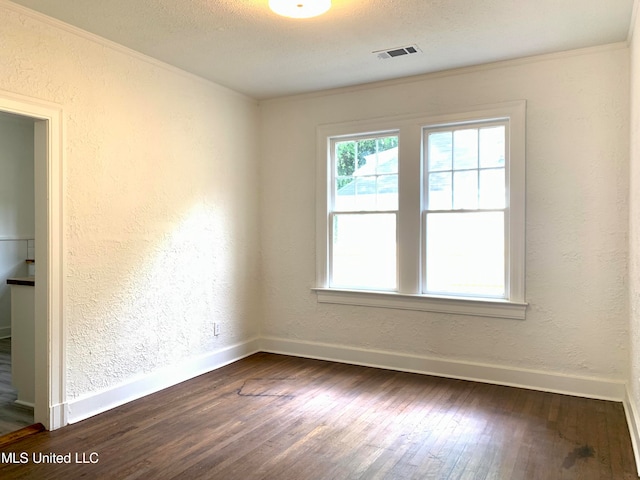 spare room with crown molding, a textured ceiling, and dark hardwood / wood-style flooring