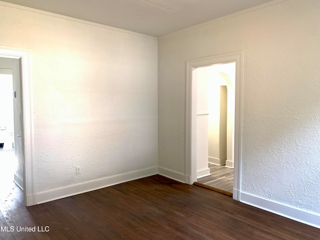 spare room featuring ornamental molding and dark hardwood / wood-style floors