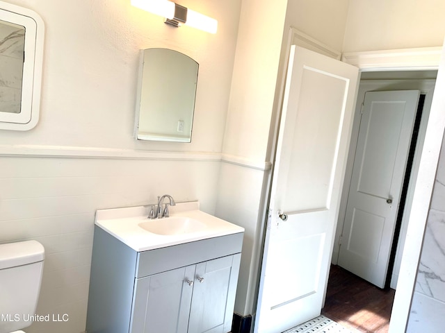 bathroom featuring vanity, toilet, tile walls, and hardwood / wood-style floors