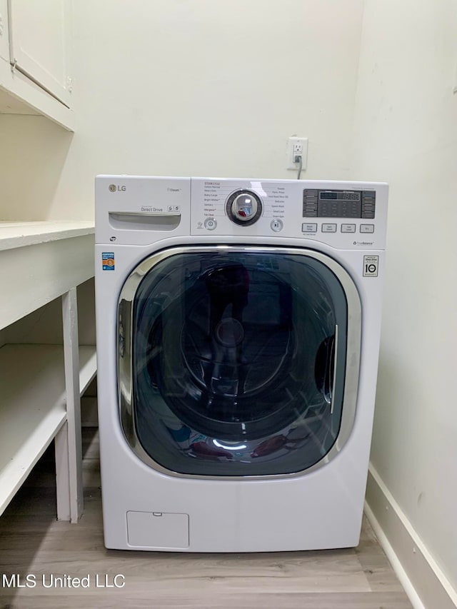 laundry area featuring washer / dryer, light wood-type flooring, and cabinets