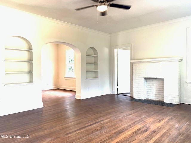 unfurnished living room featuring a fireplace, built in shelves, dark hardwood / wood-style floors, and ceiling fan