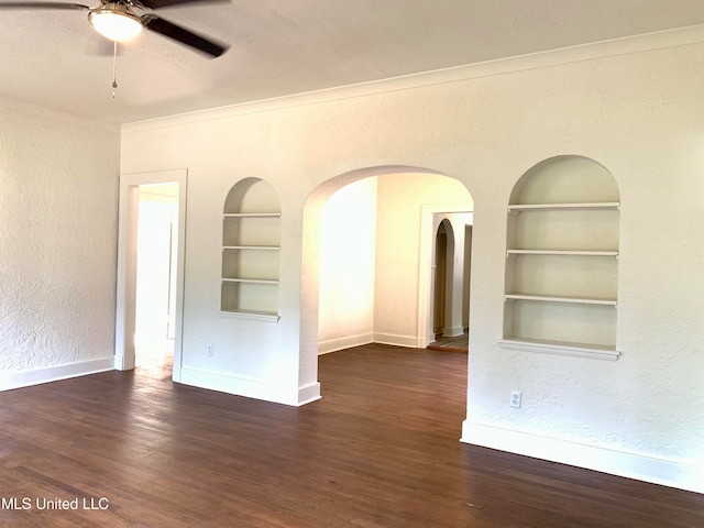 unfurnished room featuring built in shelves, dark hardwood / wood-style floors, and ceiling fan