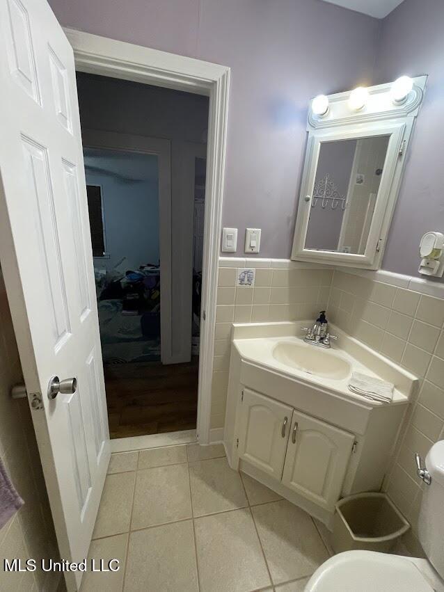 bathroom featuring toilet, vanity, tile patterned floors, and tile walls