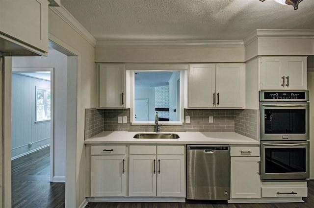 kitchen with a sink, appliances with stainless steel finishes, dark wood finished floors, and light countertops