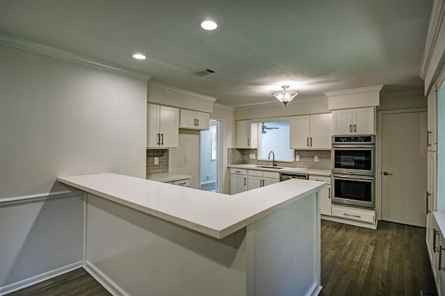 kitchen with visible vents, white cabinetry, appliances with stainless steel finishes, a peninsula, and light countertops