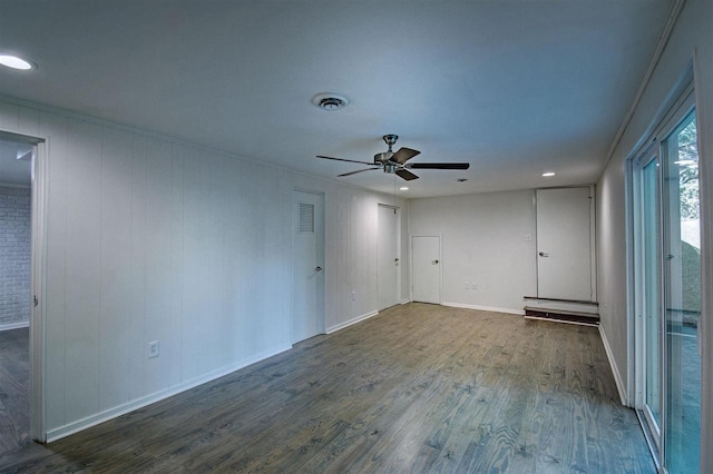 empty room featuring ceiling fan, visible vents, baseboards, and wood finished floors