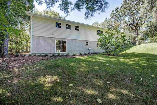 back of house with brick siding and a lawn