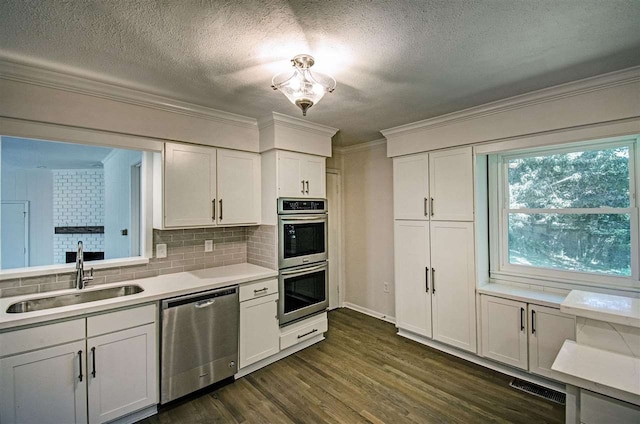 kitchen featuring crown molding, light countertops, appliances with stainless steel finishes, dark wood-style floors, and a sink