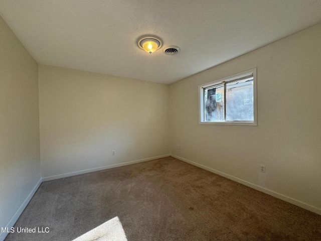 carpeted empty room with visible vents, a textured ceiling, and baseboards