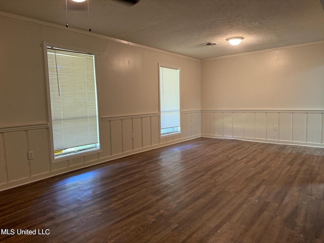 spare room with a wainscoted wall, crown molding, a textured ceiling, and dark wood-style flooring