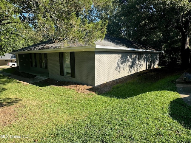 view of home's exterior with brick siding and a yard