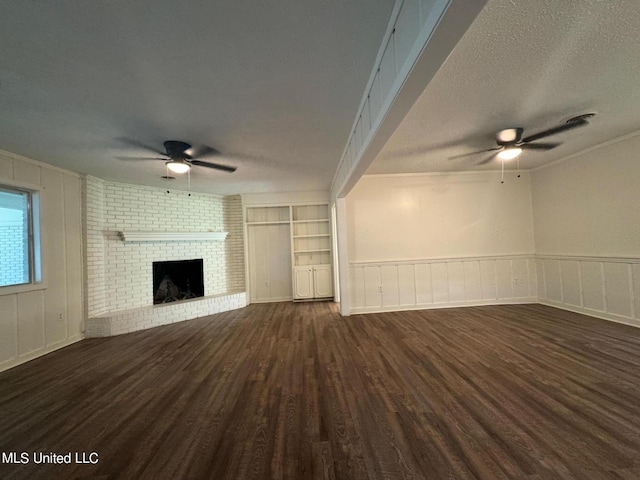 unfurnished living room with a fireplace, dark wood finished floors, ornamental molding, ceiling fan, and a textured ceiling