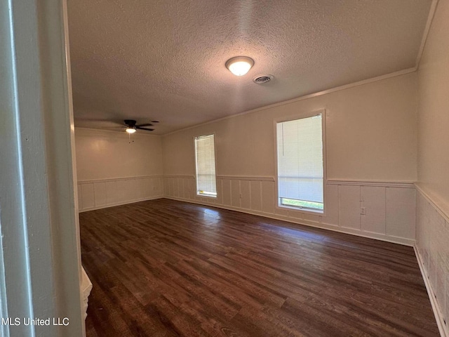 unfurnished room featuring dark wood-type flooring, a wainscoted wall, and visible vents