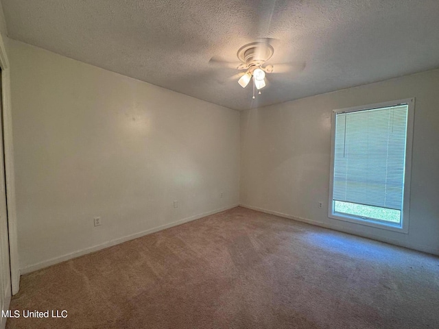 spare room with a textured ceiling, carpet flooring, a ceiling fan, and baseboards