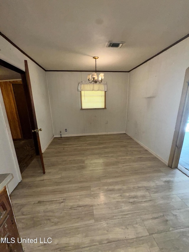 unfurnished dining area featuring visible vents, arched walkways, crown molding, light wood-type flooring, and a notable chandelier