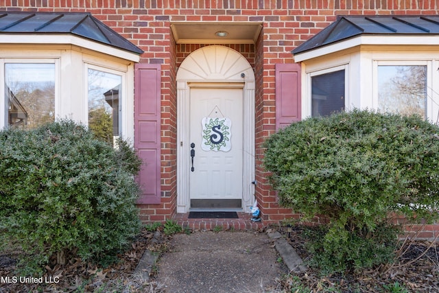 property entrance with brick siding, metal roof, and a standing seam roof