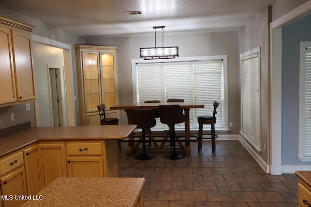 2212 Sampras Blvd, Vancleave, MS 39565 - kitchen with a peninsula, light countertops, light brown cabinets, pendant lighting, and dark tile patterned flooring