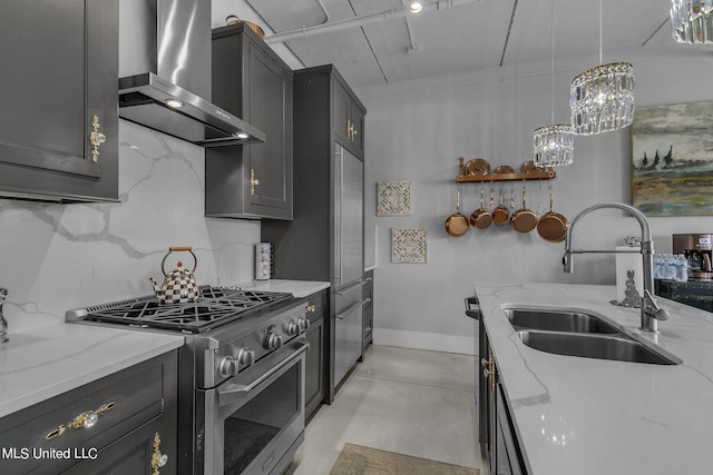 kitchen with light stone countertops, sink, wall chimney exhaust hood, decorative light fixtures, and high end appliances