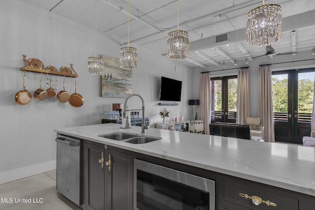 kitchen featuring sink, french doors, light stone counters, and pendant lighting