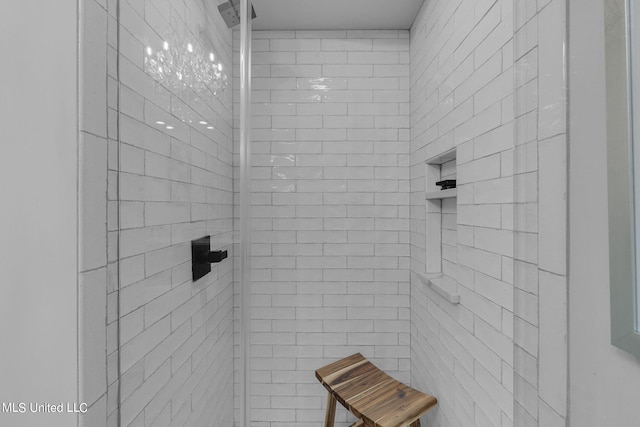 bathroom featuring a tile shower and a chandelier