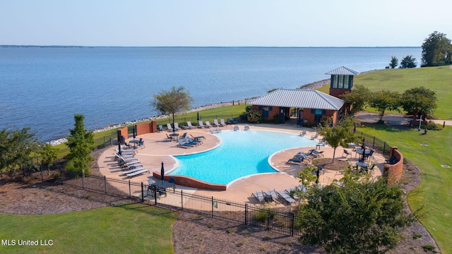 view of swimming pool with a patio area, a yard, and a water view