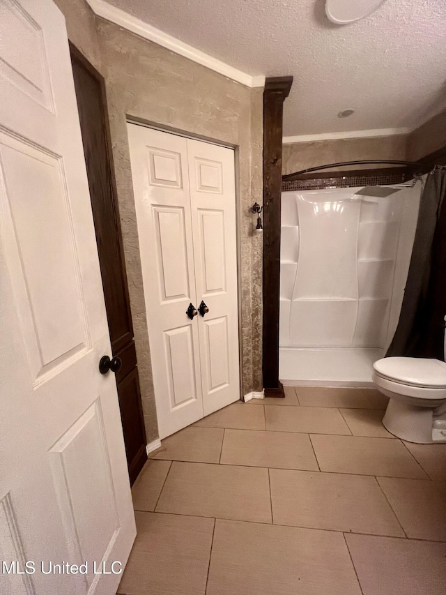 116 E Tate St, Senatobia, MS 38668 - bathroom featuring tile patterned floors, toilet, a shower with shower curtain, and a textured ceiling