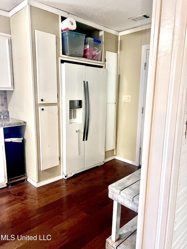 116 E Tate St, Senatobia, MS 38668 - kitchen with dark wood-style flooring, a textured ceiling, white refrigerator with ice dispenser, visible vents, and white cabinets