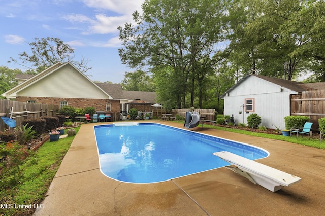 view of swimming pool featuring a water slide, a fenced backyard, a patio area, and a diving board