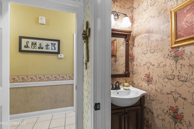 half bath with wallpapered walls, tile patterned flooring, vanity, and baseboards