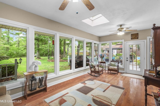 sunroom featuring a skylight, wood finished floors, and baseboards