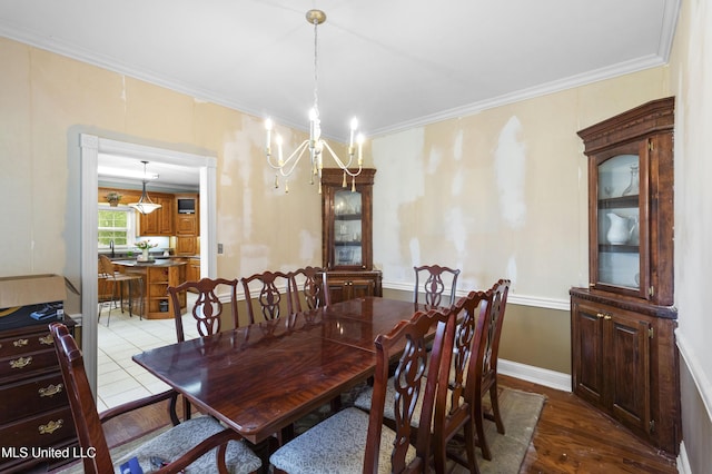 dining room with a chandelier, ornamental molding, dark wood-type flooring, and baseboards