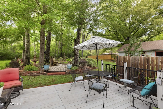 wooden terrace with outdoor dining space and fence