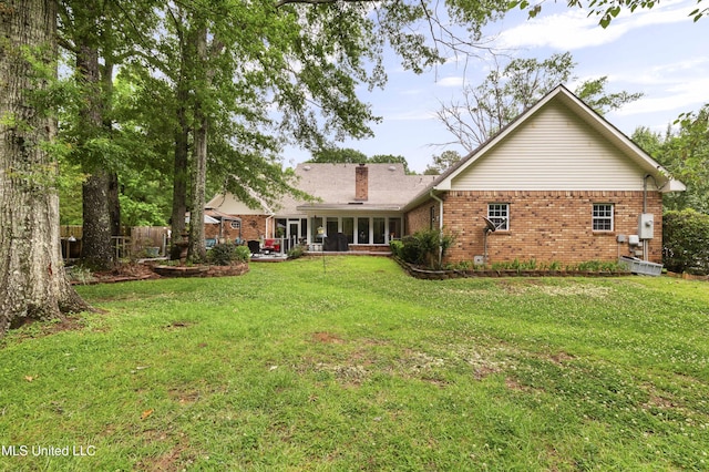 rear view of property with brick siding, a chimney, and a sunroom