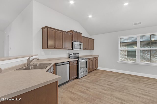 kitchen with appliances with stainless steel finishes, sink, lofted ceiling, and light hardwood / wood-style floors